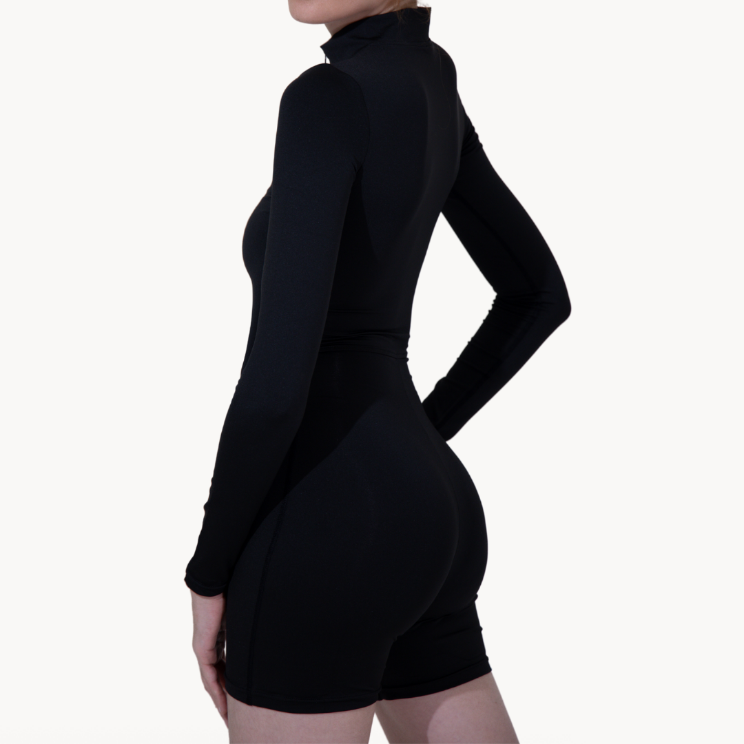 Macaquinho half mid preto ELLEVE com mangas longas, zíper frontal e efeito segunda pele. ELLEVE.COM Modelagem ajustada, tecido elástico e respirável para conforto no dia a dia ou treino. Design minimalista e versátil. ELLEVE,USELLEVE,USELLEVE.COM.